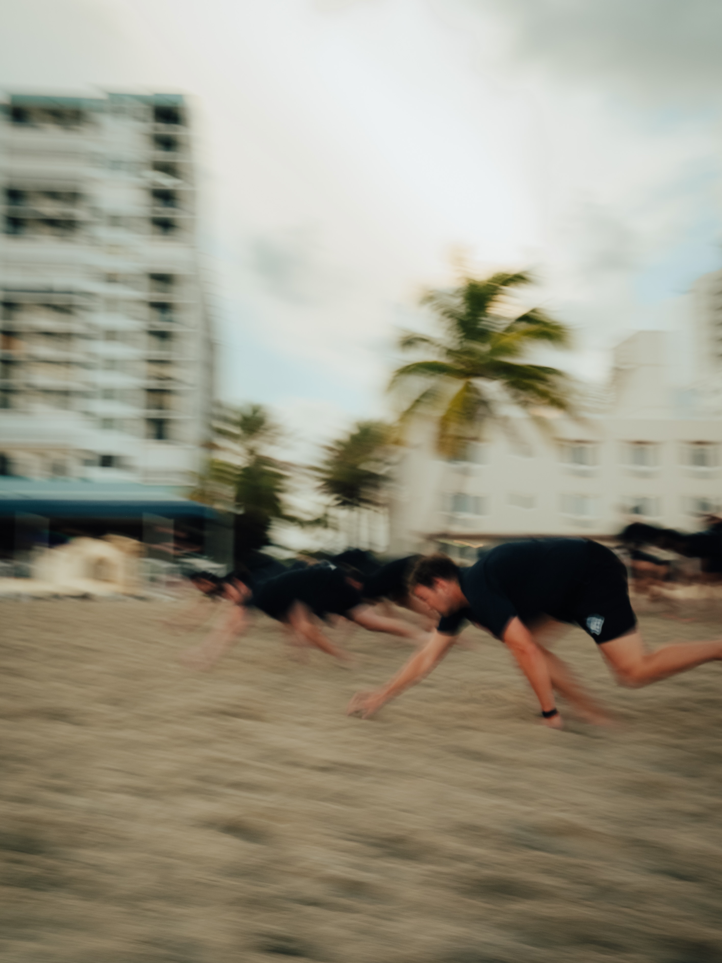 Motion-blurred team bear-crawling across the sand