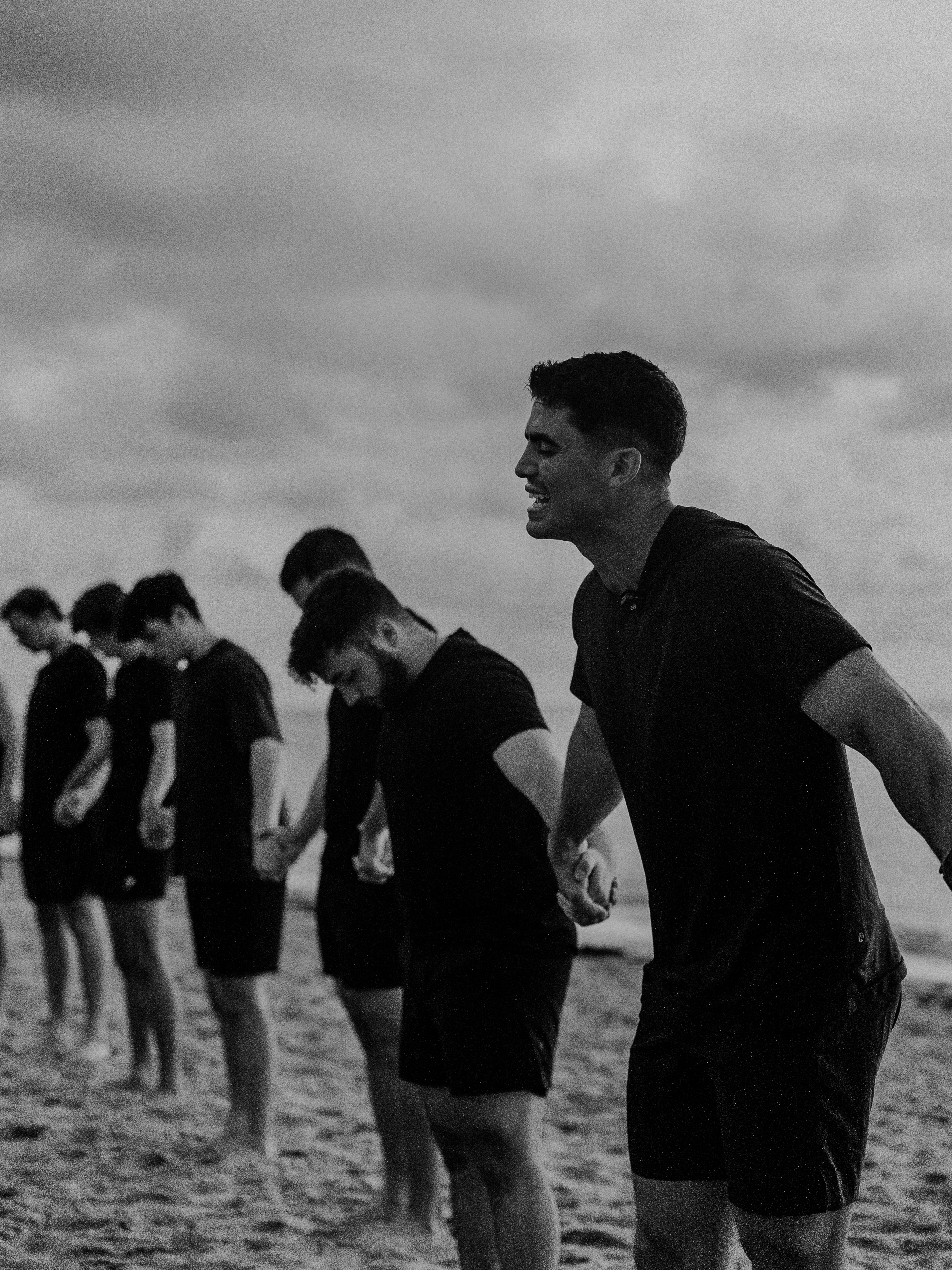 Black and white: team holding hands, heads bowed