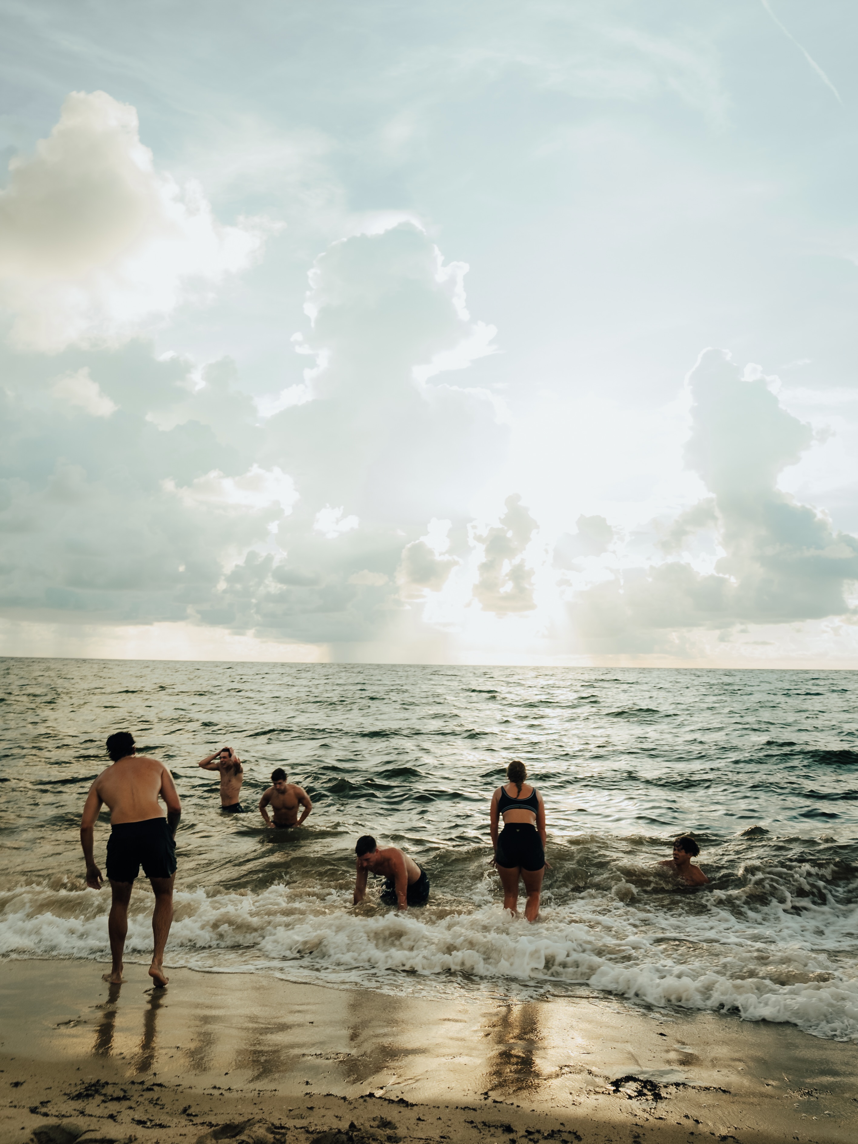 Participants wading into the ocean under breaking light